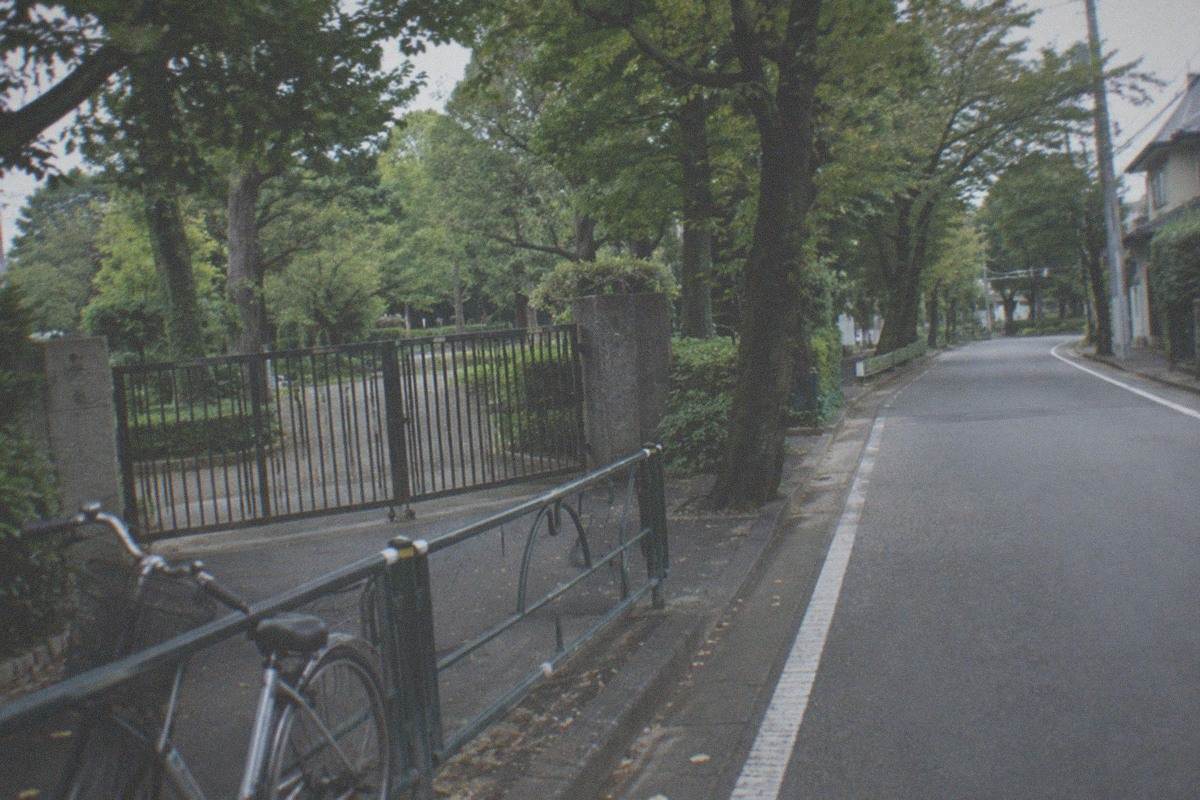 The cream and green Ghibli Museum building in Mitaka with its fenced garden under a daytime sky