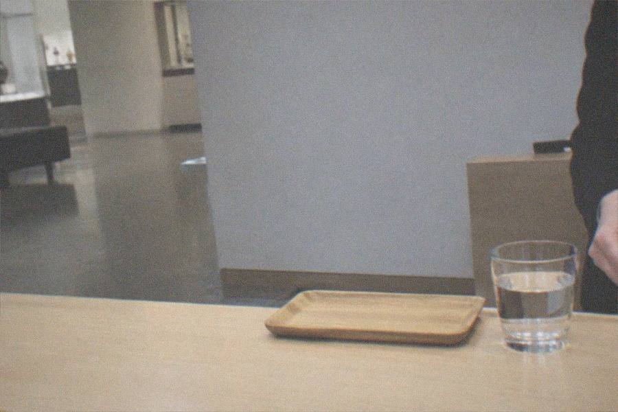 A museum ticket counter in a bright Tokyo lobby, a queue barrier curving away from it