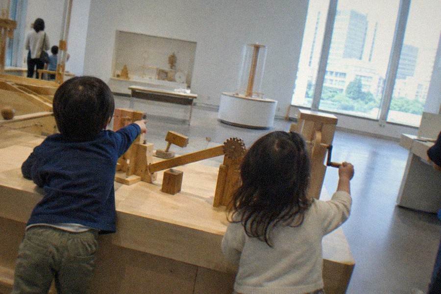 A wide museum gallery hall with polished stone floors and tall display cases along both walls