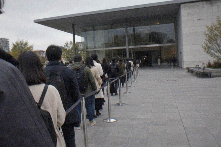 A museum entrance hall in Tokyo with a ticket machine and a small crowd checking phones